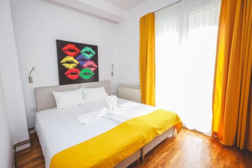 a bedroom with a white bed with a yellow blanket at AMMOTTI Hotel in Ohrid