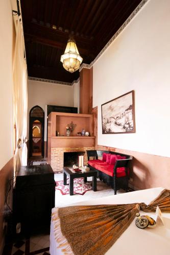 a living room with a red couch and a fireplace at Riad Alili in Marrakech