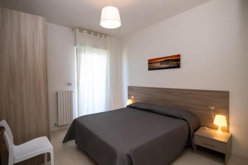 a bedroom with a bed and a white chair at Palazzina Cala Luna in San Benedetto del Tronto