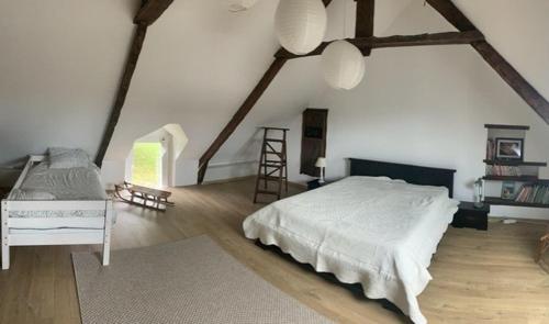 - une chambre avec un grand lit blanc et une échelle dans l'établissement Longère familiale - SAINT POTAN, à Saint-Potan
