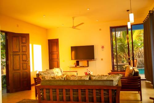 a living room with a couch and a flat screen tv at Nayan's Paradise in Kottanitivu
