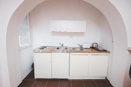 una cocina con armarios blancos y fregadero en AMMOTTI Hotel and Apartments, en Ohrid
