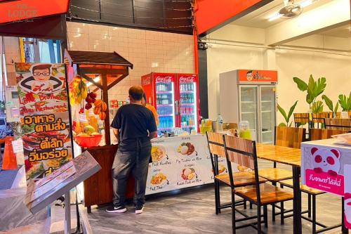 Ein Mann steht an einem Imbissstand in einem Laden in der Unterkunft The Lodge Jomtien 9 in Ban Nong Tako