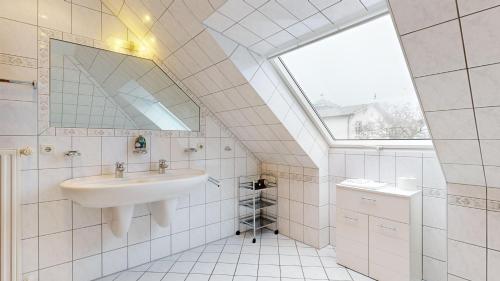 a white bathroom with a sink and a window at Villa Strandburg in Binz