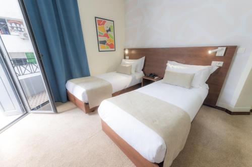 a hotel room with two beds and a window at Olympic Inn Casablanca in Casablanca