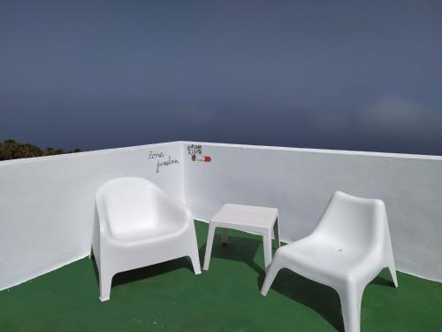 two white chairs and a stool in a room at Los atardeceres más bellos del Sauzal in Sauzal