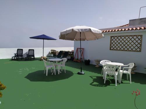 a patio with tables and chairs and an umbrella at Los atardeceres más bellos del Sauzal in Sauzal