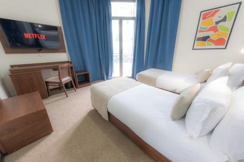 a hotel room with two beds and a television at Olympic Inn Casablanca in Casablanca