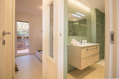 La salle de bains est pourvue d'un lavabo et d'un miroir. dans l'établissement Portisco Bouganville Seaside Charm Flat W/ Veranda, à Marina di Portisco