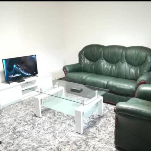 a living room with a green leather couch and a coffee table at Le Séjour in Yaoundé