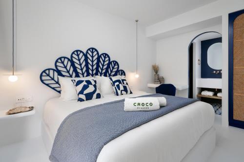 a bedroom with a large bed with blue and white pillows at Croco Mykonos in Tourlos