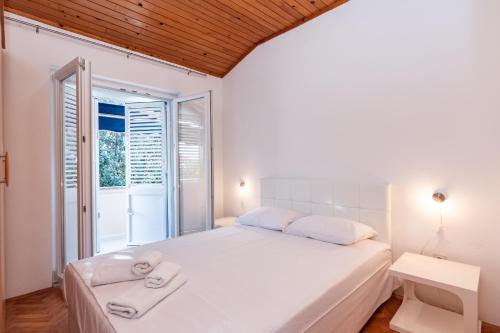 a white bedroom with a bed and a window at Apartments Tauzer in Mandre