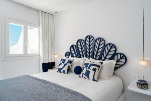 a bedroom with a large bed with blue and white pillows at Croco Mykonos in Tourlos