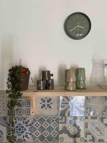 une horloge sur un mur au-dessus d'une étagère avec des pots dans l'établissement La Maison de Juliette, à Céret