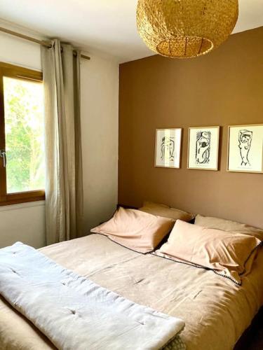 Ce lit se trouve dans une chambre dotée d'une fenêtre et d'un lustre. dans l'établissement La Maison de Juliette, à Céret