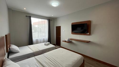 ein Hotelzimmer mit 2 Betten und einem Flachbild-TV in der Unterkunft RedDoorz Premium at Jalan Diponegoro Lampung in Bandar Lampung