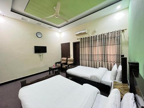 um quarto de hotel com duas camas e uma televisão em Rose Lodges Guest House em Islamabad