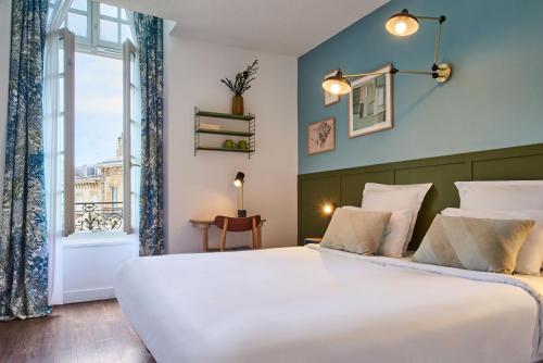 Un dormitorio con una gran cama blanca y una ventana en Hôtel Bordeaux Clémenceau by Happyculture, en Burdeos