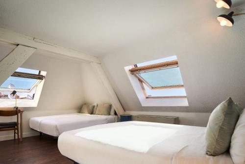 two beds in a room with two windows at Hôtel Bordeaux Clémenceau by Happyculture in Bordeaux