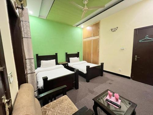 Habitación con 2 camas y pared verde. en Rose Lodges Guest House en Islamabad