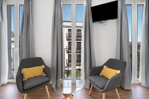 two chairs and a glass table in a room with windows at Casa Milano 2 in Jerez de la Frontera