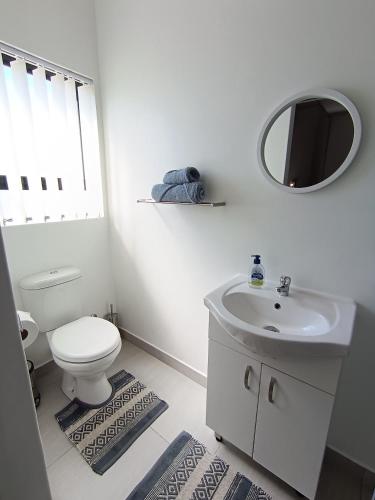 a white bathroom with a toilet and a sink at Silver Oaks Where The Clock Stops in Langebaan