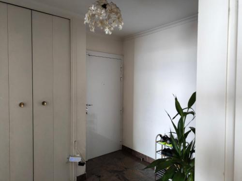 un couloir avec des murs blancs et un lustre dans l'établissement Lovely Appartment In Paris - Near Arena Porte de la Chapelle, à Paris