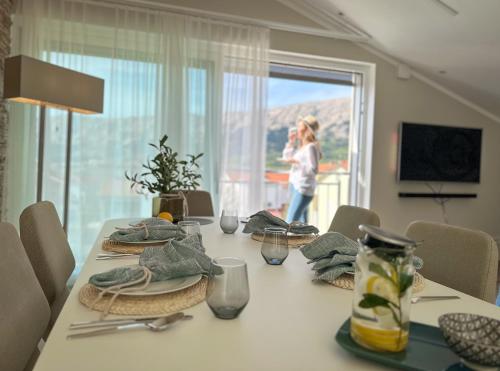 a dining room table with a woman in the window at Apartment Baska - Main Building in Baška