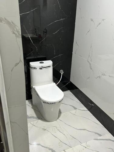 - une salle de bains avec toilettes dans une chambre noire et blanche dans l'établissement Nihaal Palace, à Ayodhya