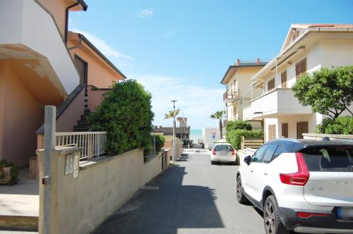 une voiture blanche garée dans une rue à côté des bâtiments dans l'établissement Casa Millo a Marina di Cecina by Zoom In Earth, à Marina di Cecina