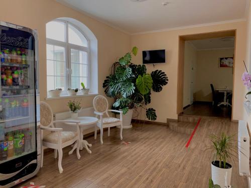 ein Wohnzimmer mit einem Tisch, Stühlen und Pflanzen in der Unterkunft Орхідея in Romny