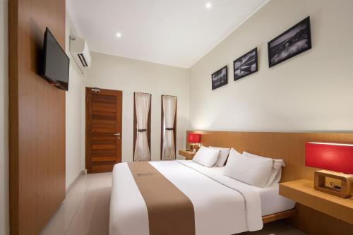 a bedroom with a large bed and a television at Angkul Angkul Segara Beach Kuta by Kamara in Kuta