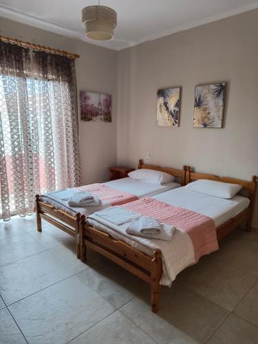 a bedroom with two beds and a window at Kostas Christos Rooms in Ammoudia