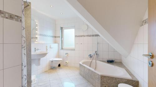 a bathroom with a tub and a toilet and a sink at Strandamsel in Binz