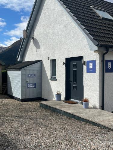 a white house with a garage and a door at View of the Mountain in North Ballachulish