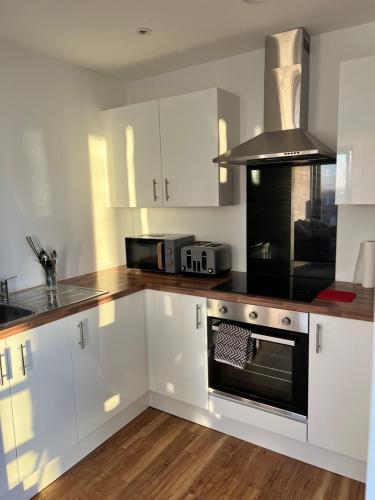 a kitchen with white cabinets and a stove top oven at 2Bed apartment in Media city within walking distance from Old Trafford Stadium in Manchester