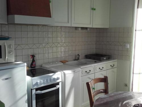 une cuisine avec des appareils électroménagers blancs et des armoires blanches dans l'établissement Gîte champêtre avec parc arboré, à 20 min du Zoo de Beauval, idéal pour petite famille. - FR-1-491-335, à Meusnes