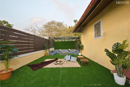 einen kleinen Hinterhof mit grünem Gras und einer Terrasse in der Unterkunft EKOSTAY - Pinewood Villa in Alibag