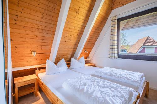 um quarto com 2 camas num quarto com uma janela em Ferienwohnpark Immenstaad am Bodensee Nurdachhaus Typ 8 NDT 113 em Immenstaad am Bodensee