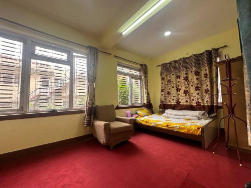 um quarto com uma cama, uma cadeira e janelas em Osho Gaurishankar Meditation Center em Catmandu