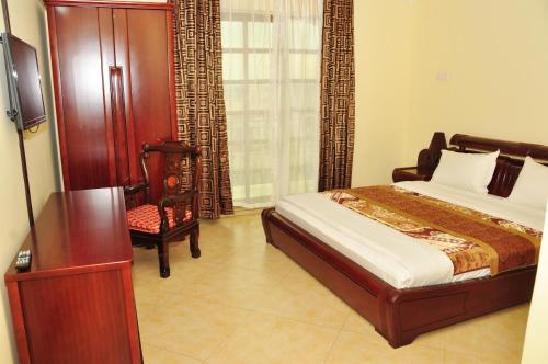 a bedroom with a bed and a chair and a window at Biraj International Hotel in Kampala