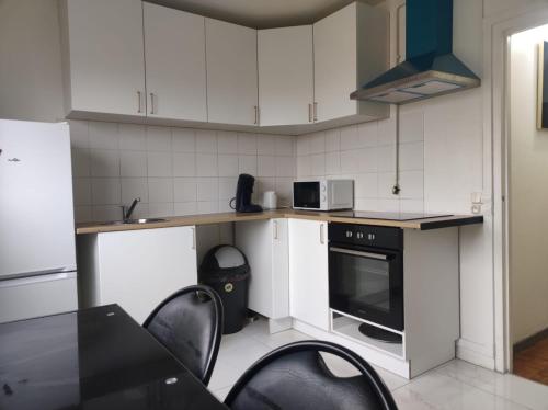 une cuisine avec des armoires blanches et des chaises noires dans l'établissement Cosy Appart Paris, à Vitry-sur-Seine