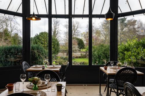 un restaurante con mesas, sillas y ventanas grandes en Maison d'Hôtes "Les Bulles Dorées", en Rilly-la-Montagne