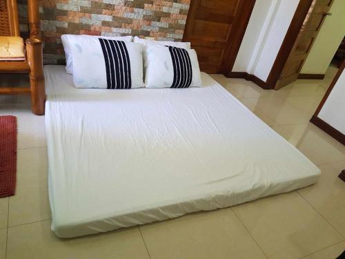 ein weißes Bett mit schwarzen und weißen Kissen darauf in der Unterkunft Homaja Roomrental in Panglao