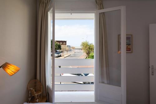 a door to a balcony with a view of a street at Hôtel De La Plage in Courseulles-sur-Mer