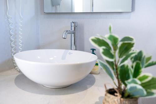 a white bowl sink on a counter with a plant at Aegean Blue Santorini Perissa in Perissa