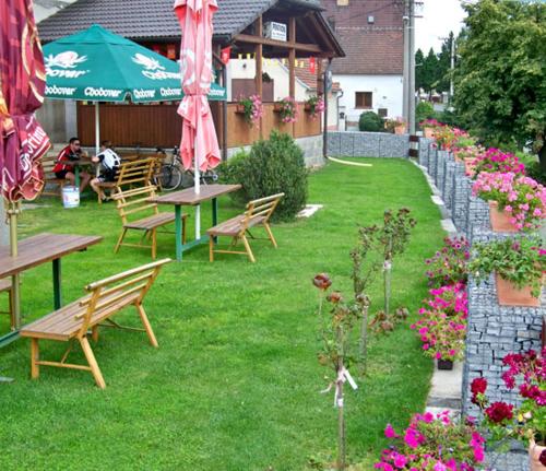 un giardino con panchine, tavoli, ombrelloni e fiori di PENZION HRADEC 