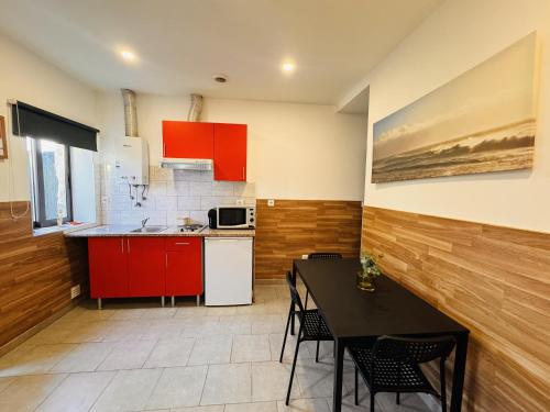 にあるCasa Luz Apartamento 2のキッチン(赤いキャビネット、黒いテーブル、椅子付)