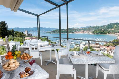 Europa Grand Hotel في ليريسي: بلكونه فيها طاولات وكراسي واطلاله على الماء