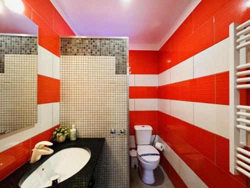 baño rojo y blanco con lavabo y aseo en Casa Luz Apartamento 3, 